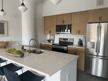 A kitchen with a white counter top and stainless steel appliances.